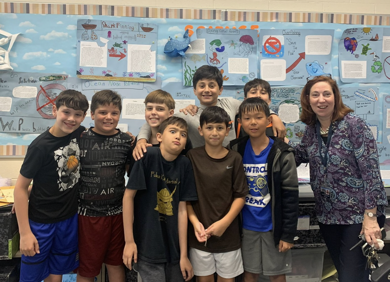 Adult standing by students in a classroom