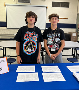Two middle school boys behind an information table